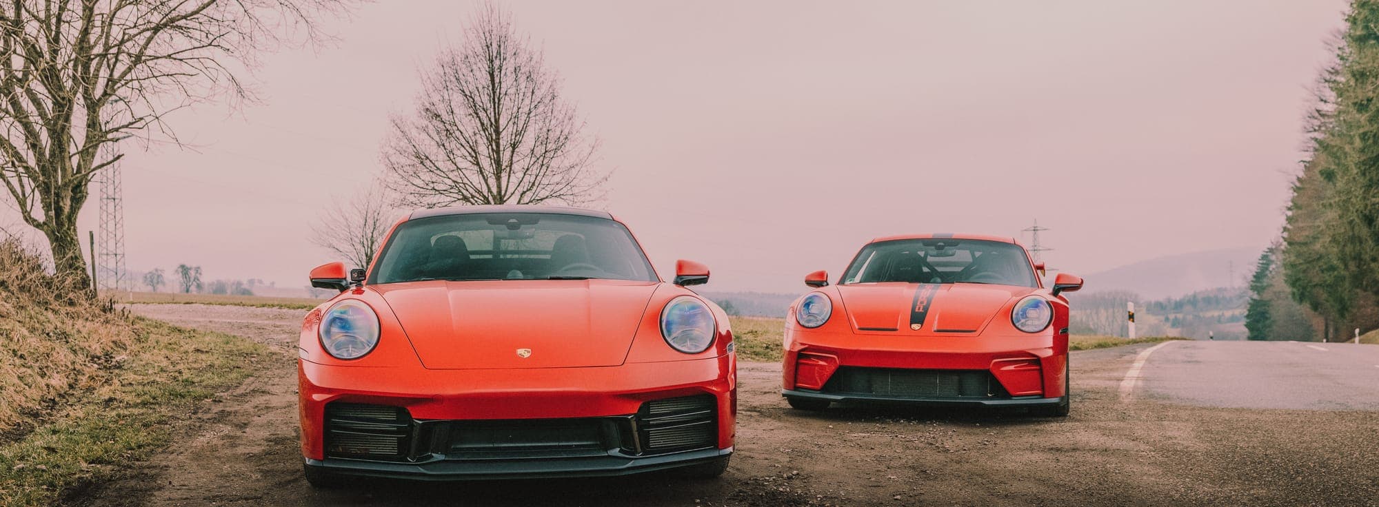 A red Porsche 911 Turbo S and Porsche 911 GT3 on a country road.