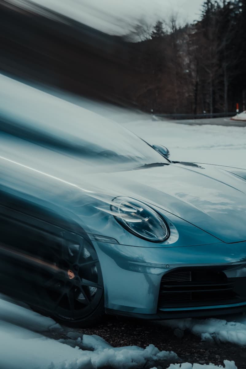 A Porsche 911 driving through a snow-covered Alpine pass.