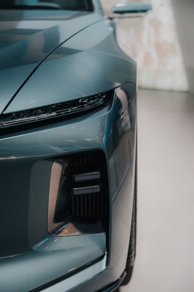 Close-up of the headlight and grille of a turquoise SUV in a showroom.
